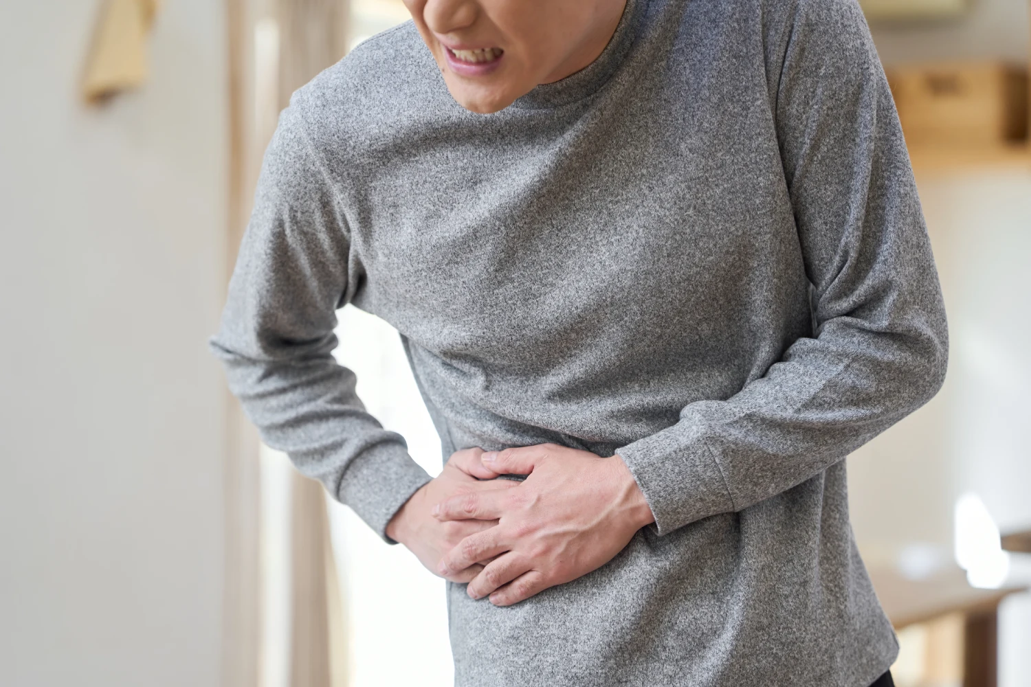 Woman holding abdomen in pain, possible gallstone symptoms